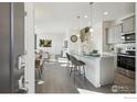Bright, open-concept kitchen with gray cabinets, stainless appliances, and a breakfast bar with pendant lighting at 18722 E 99Th Ave, Commerce City, CO 80022