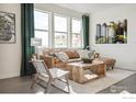 Inviting living room with large windows, modern decor, plush sofa, and stylish wood furniture at 18722 E 99Th Ave, Commerce City, CO 80022