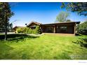 Exterior of a log home with a manicured green lawn, mature trees, and an attached garage at 2965 Wagner St, Strasburg, CO 80136