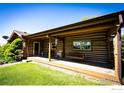 Charming log cabin home showcasing a covered porch with a wooden swing and views of the lawn at 2965 Wagner St, Strasburg, CO 80136