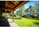 Covered porch showing exposed beams and a porch swing overlooking a spacious green lawn with mature trees at 2965 Wagner St, Strasburg, CO 80136