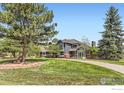 Charming two-story home featuring a well-manicured lawn, mature trees, and a brick-lined driveway at 3159 Nelson Rd, Longmont, CO 80503