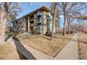 Apartment building with bay windows and small balconies on a manicured lawn at 400 Emery St # 208, Longmont, CO 80501