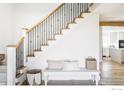 Bright entryway with elegant staircase, iron railings, and a cozy bench complemented by hardwood floors at 4932 Valkyrie Dr, Boulder, CO 80301