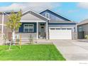 Inviting blue two-story home with a covered porch, two-car garage, and green lawn at 9940 Biscay St, Commerce City, CO 80022