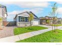 Beautiful blue home featuring a well-maintained lawn, a cozy porch, and a two-car garage at 9940 Biscay St, Commerce City, CO 80022