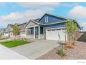 Nice blue two-story home with a front porch, two-car garage, and beautifully landscaped front yard at 9940 Biscay St, Commerce City, CO 80022