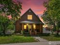 Charming brick home featuring a classic design, landscaped yard, and inviting front porch at dusk at 101 Se 2Nd St, Berthoud, CO 80513
