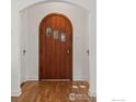 Stunning arched wooden front door with decorative glass panels, complemented by hardwood floors and white trim at 1035 Spruce St, Boulder, CO 80302