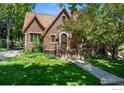 Charming brick home features a tile roof, arched entry, and inviting front porch with lush landscaping at 1035 Spruce St, Boulder, CO 80302