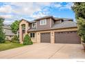 Well-maintained two-story home with brick and brown siding, mature trees and a three-car garage at 13971 Telluride Dr, Broomfield, CO 80020