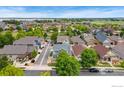 Panoramic aerial view of the neighborhood showcasing lush green trees, diverse housing, and serene waters in the distance at 1424 Bluemoon Dr, Longmont, CO 80504