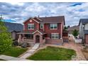 Beautiful two-story home featuring brick accents and a covered porch with a well-manicured lawn at 2190 Winding Dr, Longmont, CO 80504