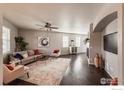 Cozy living room with modern furnishings, ceiling fan, fireplace, and dark wood floors at 2190 Winding Dr, Longmont, CO 80504