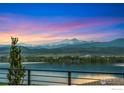 Stunning lake view at sunset with snow-capped mountains in the distance, showcasing the natural beauty of the property at 2387 Harding Park Ct, Berthoud, CO 80513