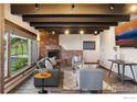 Inviting living room features a cozy brick fireplace, exposed beams, and large windows offering ample natural light at 3021 N Lakeridge Trl, Boulder, CO 80302