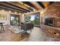 Comfortable living room features a charming brick fireplace, wood flooring, and scenic views from the large windows at 3021 N Lakeridge Trl, Boulder, CO 80302