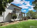 Side view of a well-maintained home with a green lawn and mature landscaping at 395 Longspur Dr, Brighton, CO 80601