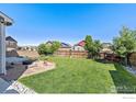 Expansive backyard with lush green grass, a fire pit, and a wood fence at 6681 6Th St, Frederick, CO 80530