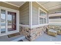 Covered front porch with a seating area, decorative stone accents, and a welcoming front door at 8852 E 152Nd Ct, Thornton, CO 80602