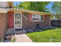 Close up front entrance featuring brick facade, decorative door and vibrant green lawn at 9084 W Rice Ave, Littleton, CO 80123