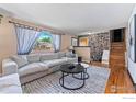 Spacious living room featuring a decorative stone wall, hardwood floors and a large window at 9084 W Rice Ave, Littleton, CO 80123