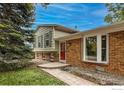 Charming single-Gathering home with a well-maintained lawn and mature trees, accented by a red front door at 117 Sandler Dr, Lafayette, CO 80026