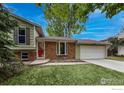 Charming single-Gathering home with a well-maintained lawn and mature trees, accented by a red front door at 117 Sandler Dr, Lafayette, CO 80026