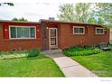 A charming brick house featuring a well-manicured lawn and walkway leading to the front door with well kept landscape at 1204 Sherri Mar Ct, Longmont, CO 80501