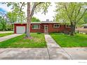 Classic brick home with a well-kept lawn, mature trees, a driveway to the garage, and a welcoming walkway to the front door at 1204 Sherri Mar Ct, Longmont, CO 80501