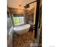 Beautiful bathroom with stone floors, free standing tub and modern shower at 12742 Clermont St, Thornton, CO 80241