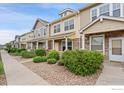 View of the townhome exteriors with stone accents and well-maintained front yard landscaping at 13624 Garfield St # B, Thornton, CO 80602