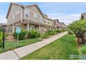 A sidewalk leads past multiple townhomes, each with stone accents and pleasant landscaping at 13624 Garfield St # B, Thornton, CO 80602
