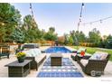 Inviting outdoor living space with comfortable seating, a patterned rug, and views of the pool and manicured lawn at 1505 Oak Ave, Boulder, CO 80304
