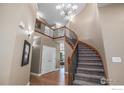 Grand foyer with a curved staircase, hardwood floors, a chandelier, and neutral wall colors at 15562 E 109Th Ave, Commerce City, CO 80022