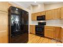 Well-lit kitchen with wood cabinets and black appliances, including a refrigerator and oven at 2421 Maplewood W Cir, Longmont, CO 80503