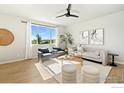 Bright living room with hardwood floors, modern ceiling fan, and a large window offering scenic views at 2672 Prairiestar Dr, Berthoud, CO 80513