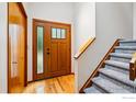 Inviting entryway with hardwood floors, a wood door with glass, carpeted stairs, and wood railing at 4489 Wellington Rd, Boulder, CO 80301