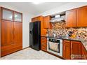 The updated kitchen features stainless appliances, wood cabinetry, and stylish mosaic backsplash at 4489 Wellington Rd, Boulder, CO 80301