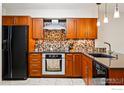 Modern kitchen with stainless steel appliances, cherry cabinets, black countertops, and stylish backsplash at 4489 Wellington Rd, Boulder, CO 80301