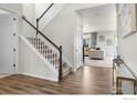 Inviting home entryway featuring hardwood floors, staircase with modern white railing, and access to the living area at 6229 Black Mesa Rd, Frederick, CO 80516