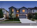 Inviting two-story home with gray siding, a well-maintained lawn, and warm interior lights shining through the windows at 6229 Black Mesa Rd, Frederick, CO 80516