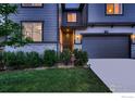 Close-up of a home featuring gray siding, a two-car garage, and a manicured lawn leading up to the front door at 6229 Black Mesa Rd, Frederick, CO 80516