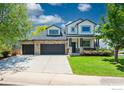 Beautifully landscaped two-story home with a stone facade, attached three-car garage, and green lawn at 6488 Tilbury Ave, Firestone, CO 80504