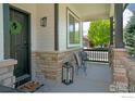 Welcoming front porch with stone columns, outdoor seating, and a decorative wreath on the front door at 6488 Tilbury Ave, Firestone, CO 80504