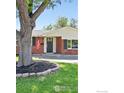 Charming brick home featuring well-manicured lawn and mature shade tree at 8290 Chase Way, Arvada, CO 80003