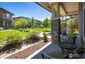 Inviting covered porch with comfortable seating, offering a tranquil view of the well-manicured lawn at 11033 E 28Th Pl, Denver, CO 80238