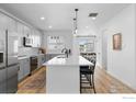 Bright kitchen showcasing an island with bar stool seating, stainless appliances and fixtures, and hardwood floors at 12155 W 57Th Pl, Arvada, CO 80002