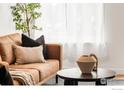 Close up of an elegant living room with a cozy leather sofa, decorative pillows, and natural light through sheer curtains at 135 E 8Th Ave, Denver, CO 80203
