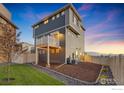 Exterior view of fenced backyard featuring a rock border with mulch, grass, and access to sliding glass door at 542 Highlands Cir, Erie, CO 80516